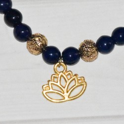 Bracelet élastique, en perles de verre teinté bleu foncé et fleur de Lotus en métal doré, détail.